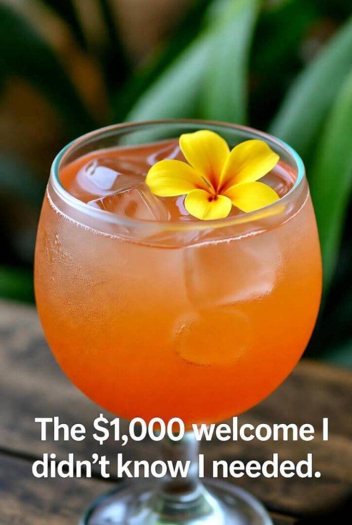close-up of a tropical welcome drink with flowers floating—captioned: “The $1,000 welcome I didn’t know I needed.” close-up of a tropical welcome drink with flowers floating—captioned: “The $1,000 welcome I didn’t know I needed.”