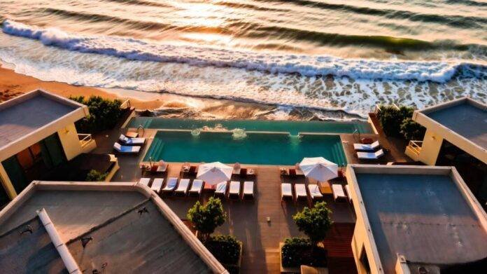 A slightly sun-drenched aerial view of a coastal resort in Malibu at golden hour—ocean waves curling, infinity pools glinting. A slightly sun-drenched aerial view of a coastal resort in Malibu at golden hour—ocean waves curling, infinity pools glinting.